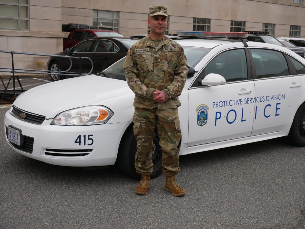 a soldier standing next to a police car