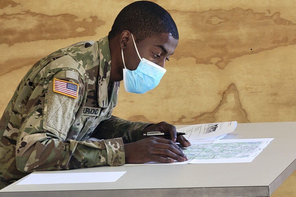 a soldier wearing a face mask and writing on a piece of paper.