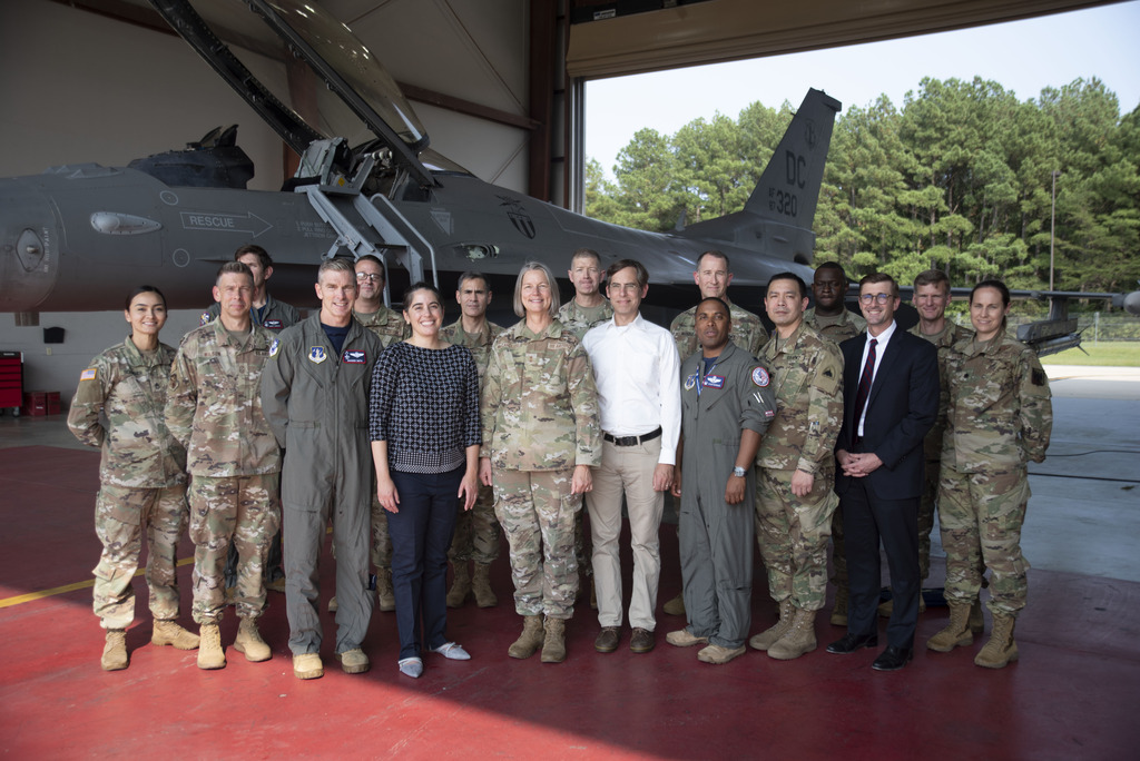 a group of soldiers standing outside a fighter jet and posing for a photograph